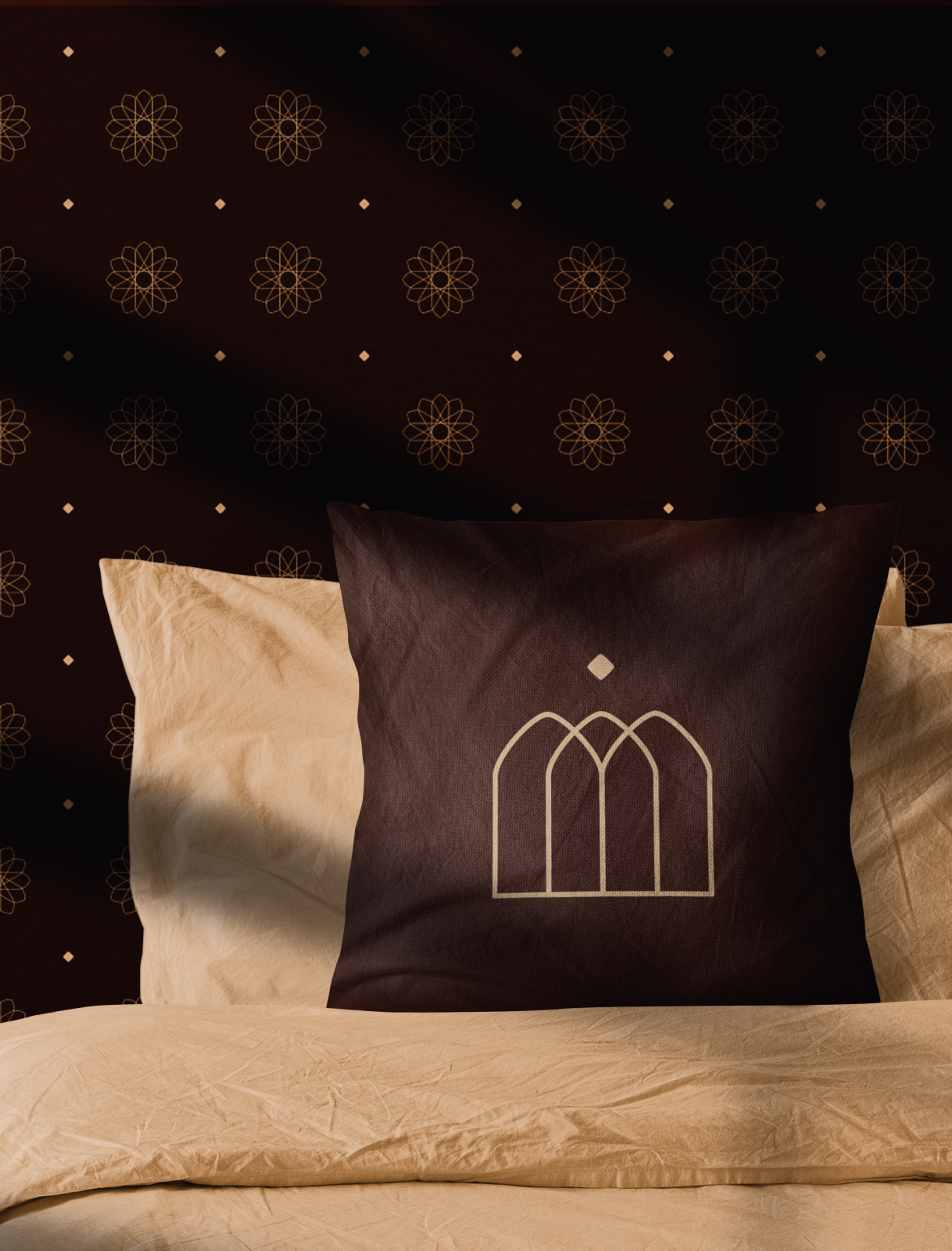 Dunkles Kissen mit goldener Stickerei des Strasserwirt-Logos, arrangiert vor einer luxuriösen braunen Wand – Unerwartet Design