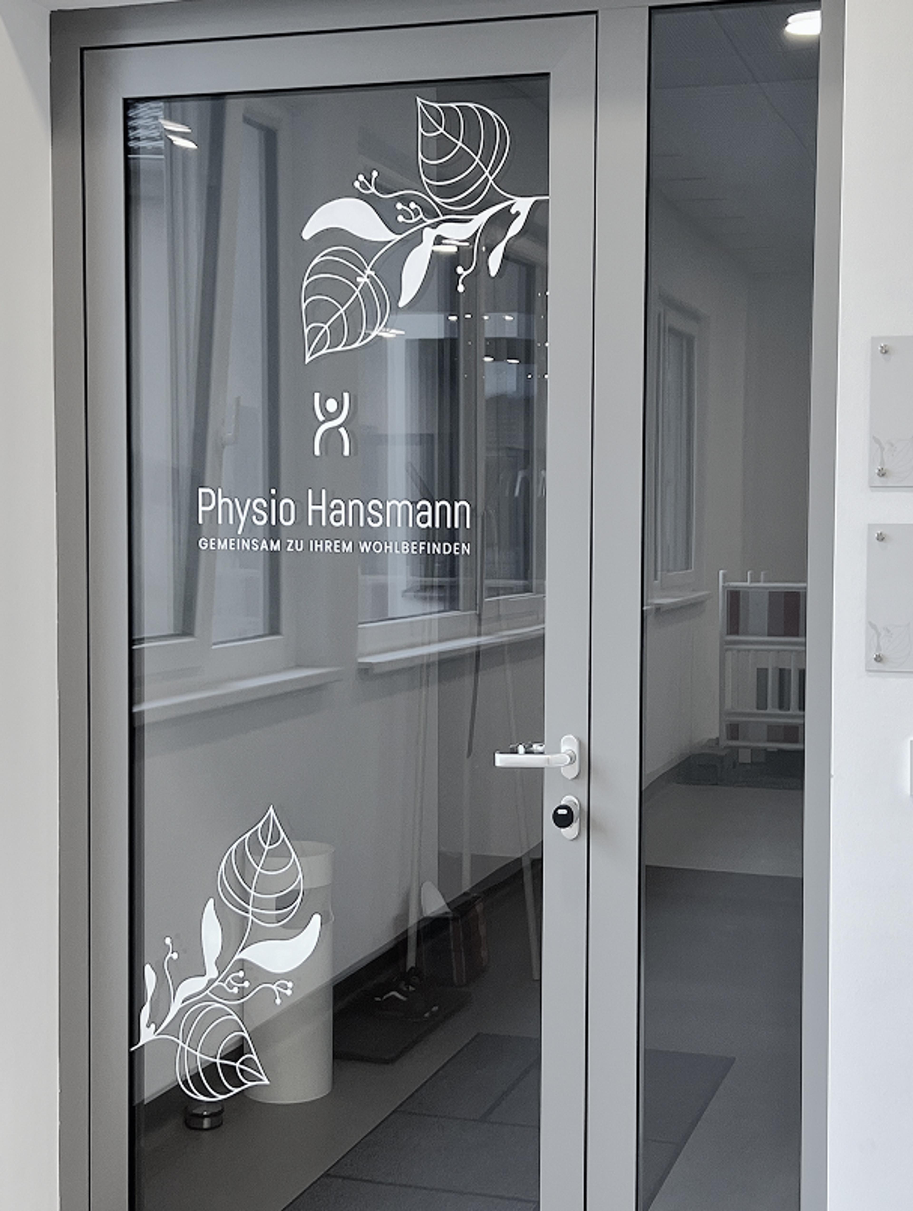 Glas-Eingangstür von Physio Hansmann mit weißem Logo und Blätter-Design. Modernes und minimalistisches Branding für das Gesundheitszentrum Lindenpark in Gössendorf.