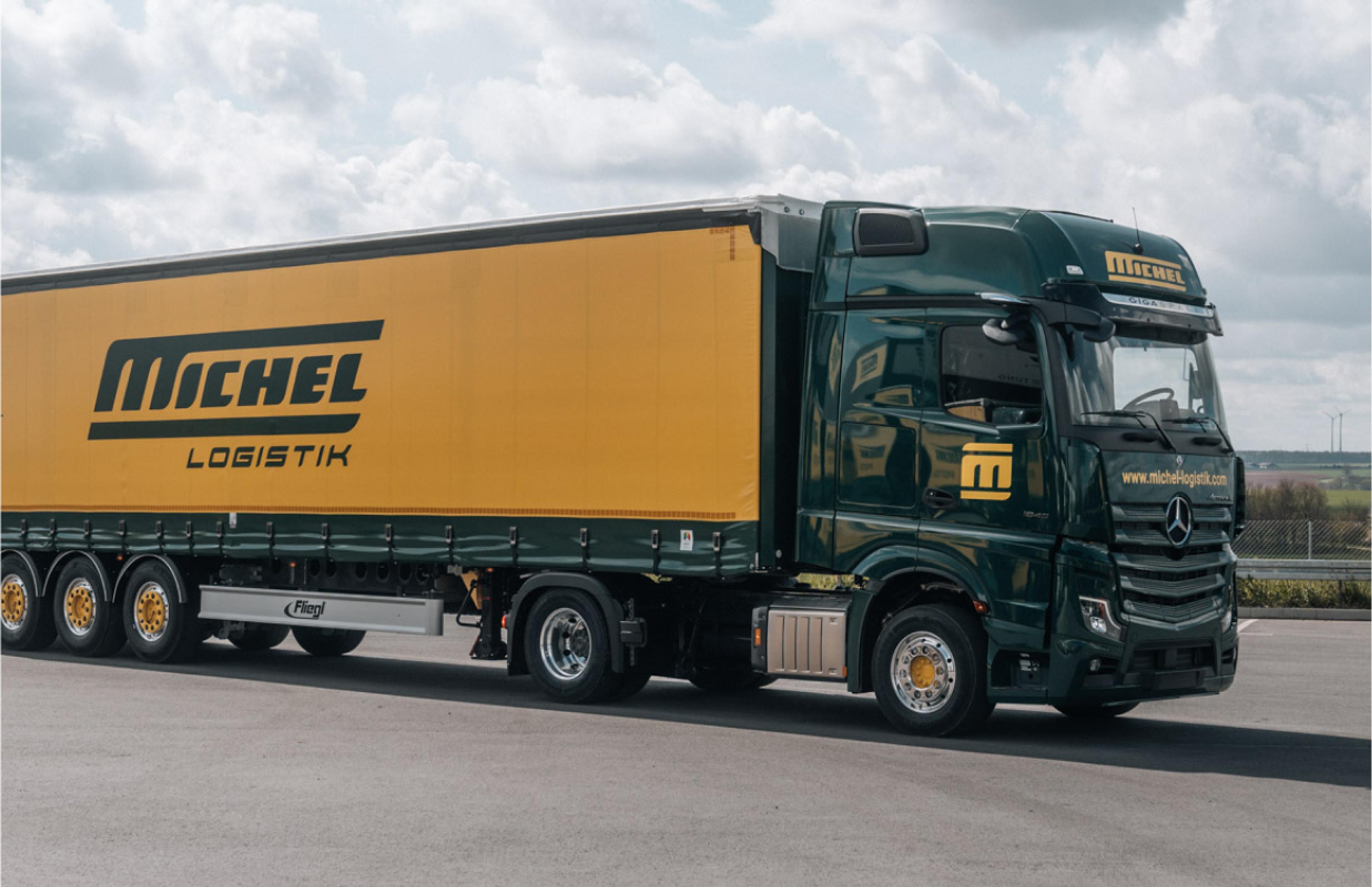 Gelb-grüner LKW mit Michel Logistik Branding auf einem Parkplatz – Design und Identität entwickelt von Unerwartet Design.