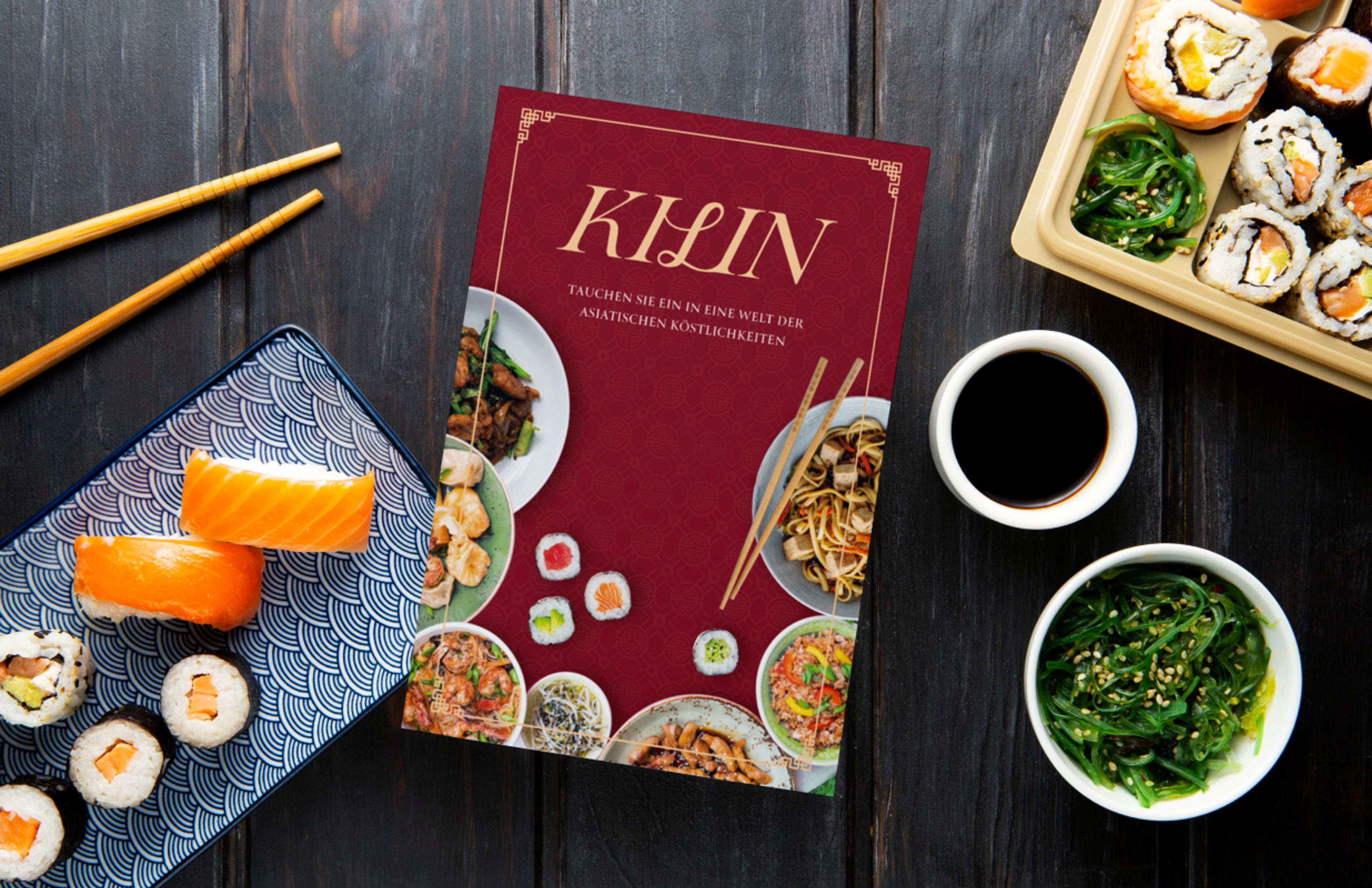 Edles Branding für das Kilin Restaurant mit luxuriösem, asiatisch inspiriertem Design. Eine Speisekarte mit goldenen Details liegt neben frisch zubereitetem Sushi und Meeresalgen-Salat. Perfekte Kombination aus hochwertiger Gastronomie, stilvollem Printdesign und moderner Markenidentität. Gestaltung und Konzept von Unerwartet Branding und Design OG aus Graz, Österreich.