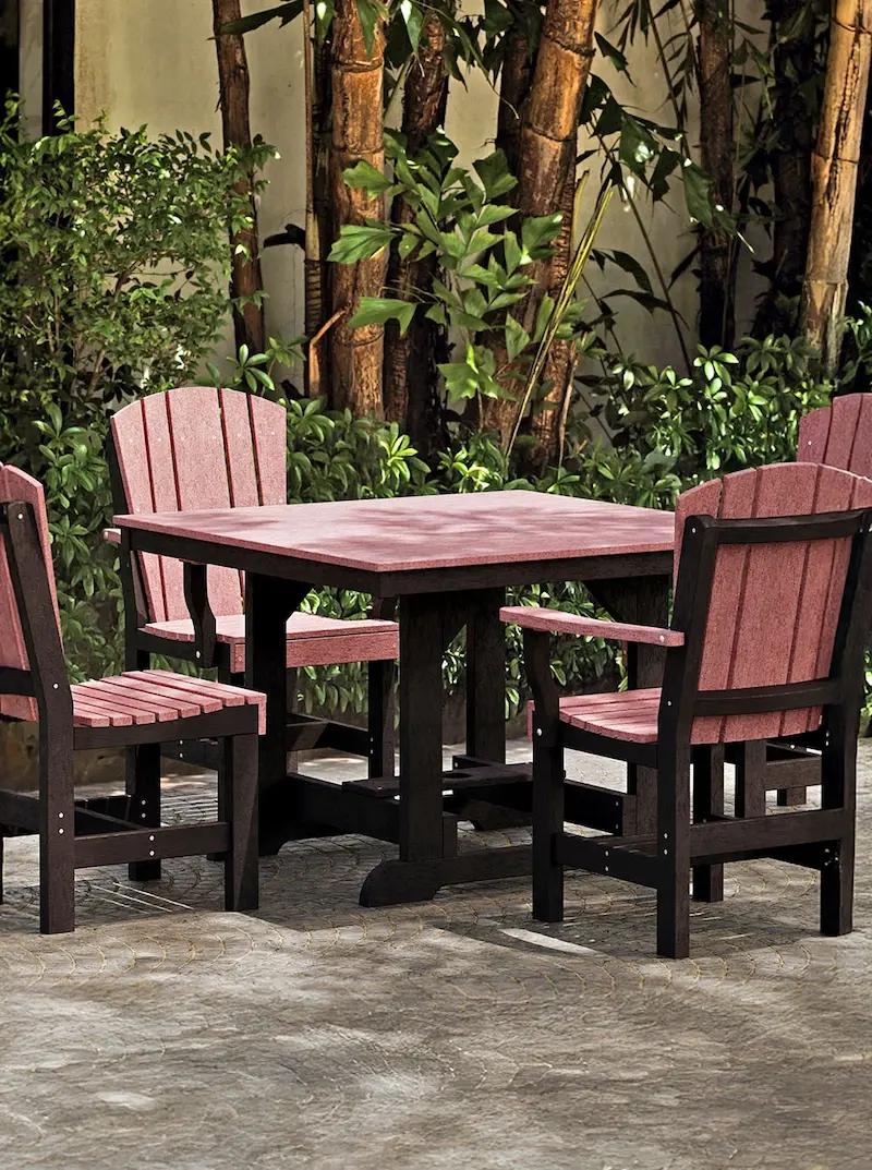 Outdoor square dining table set with four Adirondack-style chairs in red and black on a patio