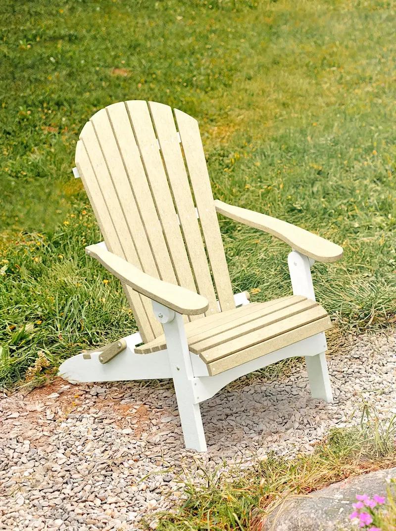 Outdoor Adirondack chair with slatted back and armrests placed on gravel with grass background.