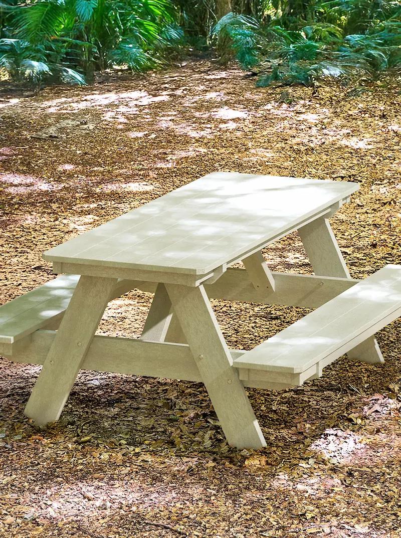 Rectangular picnic table with attached benches in a wooded outdoor setting.