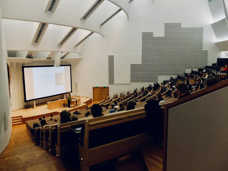 Students in a filled lecture hall watching a presentation, illustrating how traditional academic environments can breed intellectual overconfidence