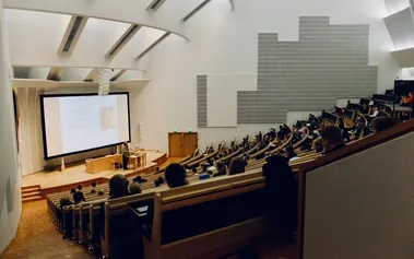 Students in a filled lecture hall watching a presentation, illustrating how traditional academic environments can breed intellectual overconfidence