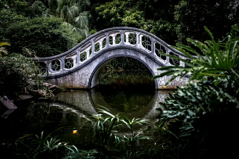 A graceful bridge connecting two sides over peaceful water, representing how strategic communication maintains relationships while setting boundaries