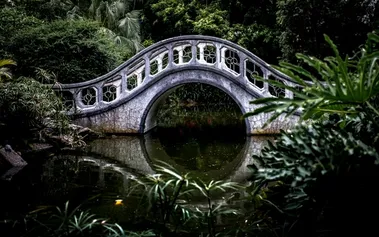 A graceful bridge connecting two sides over peaceful water, representing how strategic communication maintains relationships while setting boundaries
