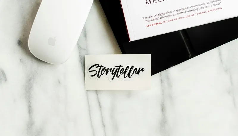 Minimalist workspace with storyteller card and laptop, symbolising the integration of storytelling frameworks into business strategy presentations