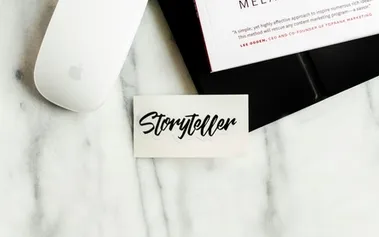 Minimalist workspace with storyteller card and laptop, symbolising the integration of storytelling frameworks into business strategy presentations