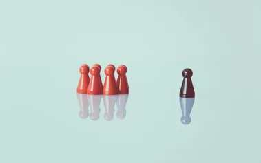 A lone dark game piece standing apart from a group of red pieces, illustrating leadership independence and confidence