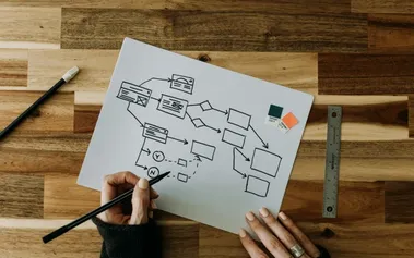 Hands sketching a business continuity flowchart on paper, illustrating strategic resilience planning that transforms crisis preparedness into competitive advantage
