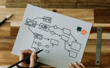 Hands sketching a business continuity flowchart on paper, illustrating strategic resilience planning that transforms crisis preparedness into competitive advantage