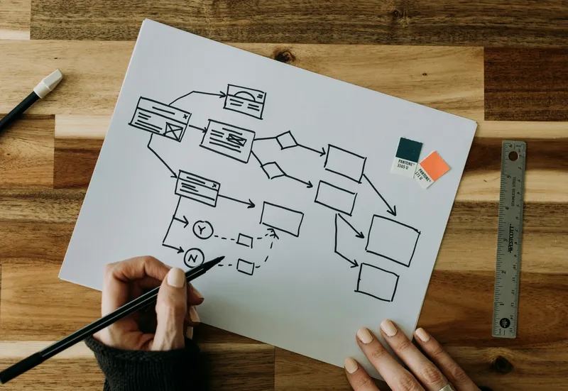 Hands sketching a business continuity flowchart on paper, illustrating strategic resilience planning that transforms crisis preparedness into competitive advantage