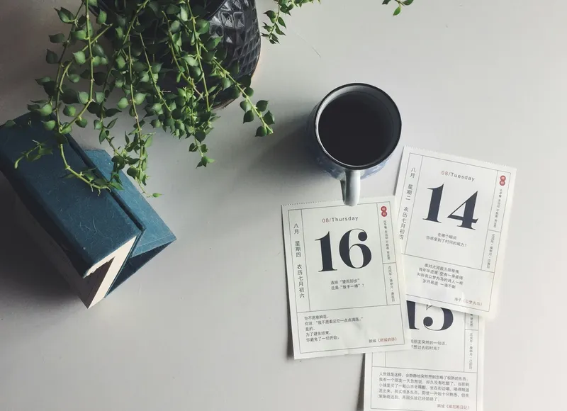 Calendar pages with coffee on desk, representing ongoing workplace conversations rather than formal annual review scheduling
