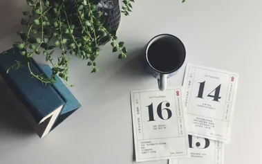 Calendar pages with coffee on desk, representing ongoing workplace conversations rather than formal annual review scheduling