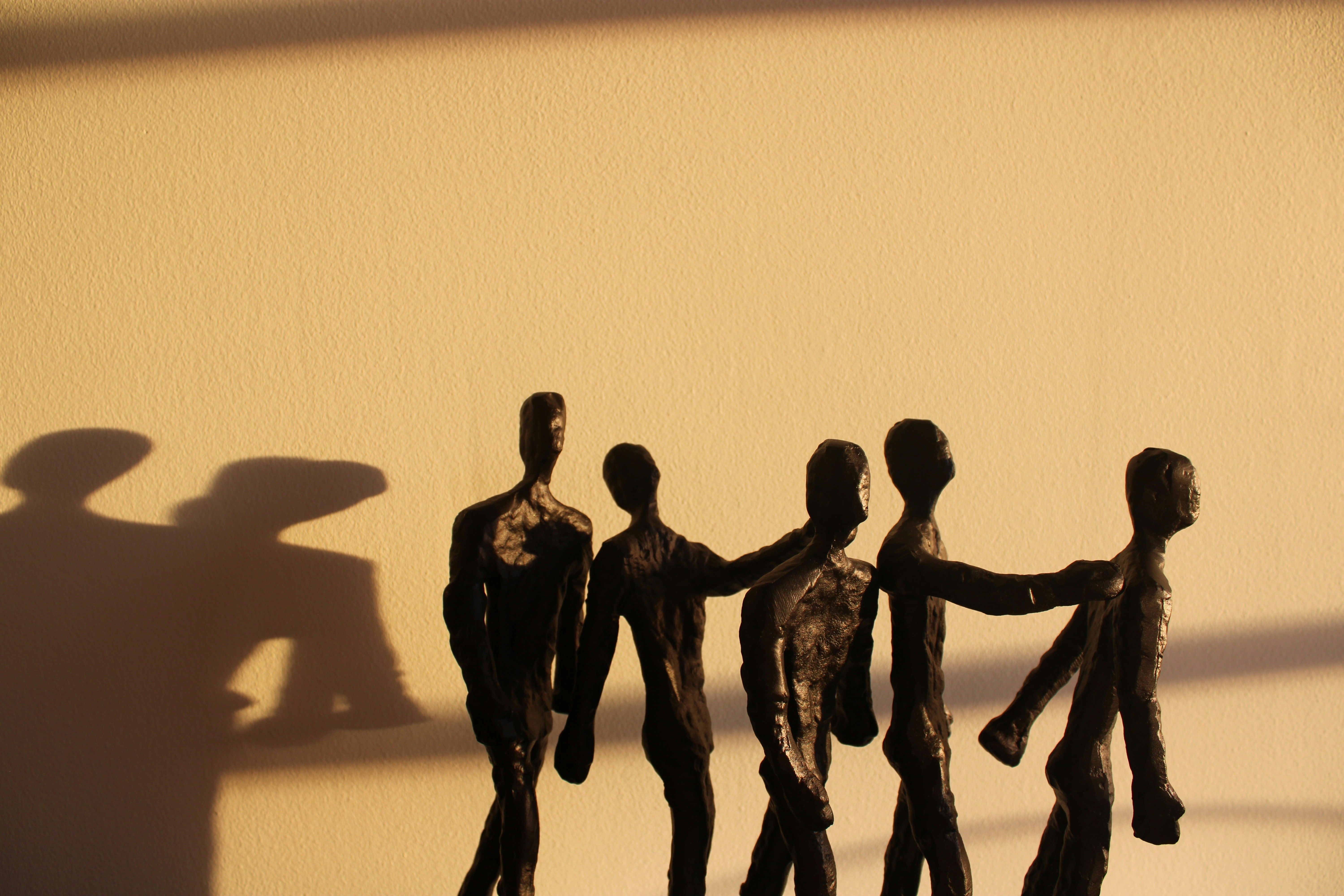 Five weathered figures connected in solidarity, representing resilient inclusion that strengthens through connection