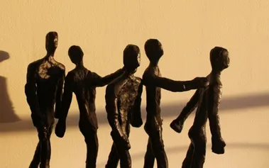 Five weathered figures connected in solidarity, representing resilient inclusion that strengthens through connection