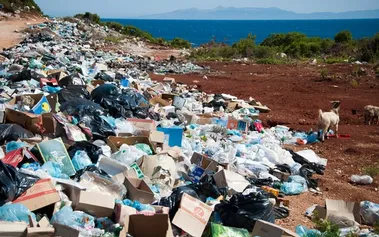 Massive landfill waste dump with plastic bottles and packaging scattered across landscape, showing environmental reality behind corporate green claims
