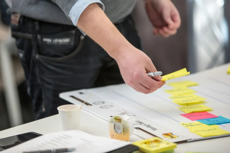 A leader organising strategic planning materials with sticky notes on documents, illustrating the systematic approach needed to balance innovation initiatives with operational priorities.