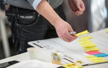 A leader organising strategic planning materials with sticky notes on documents, illustrating the systematic approach needed to balance innovation initiatives with operational priorities.