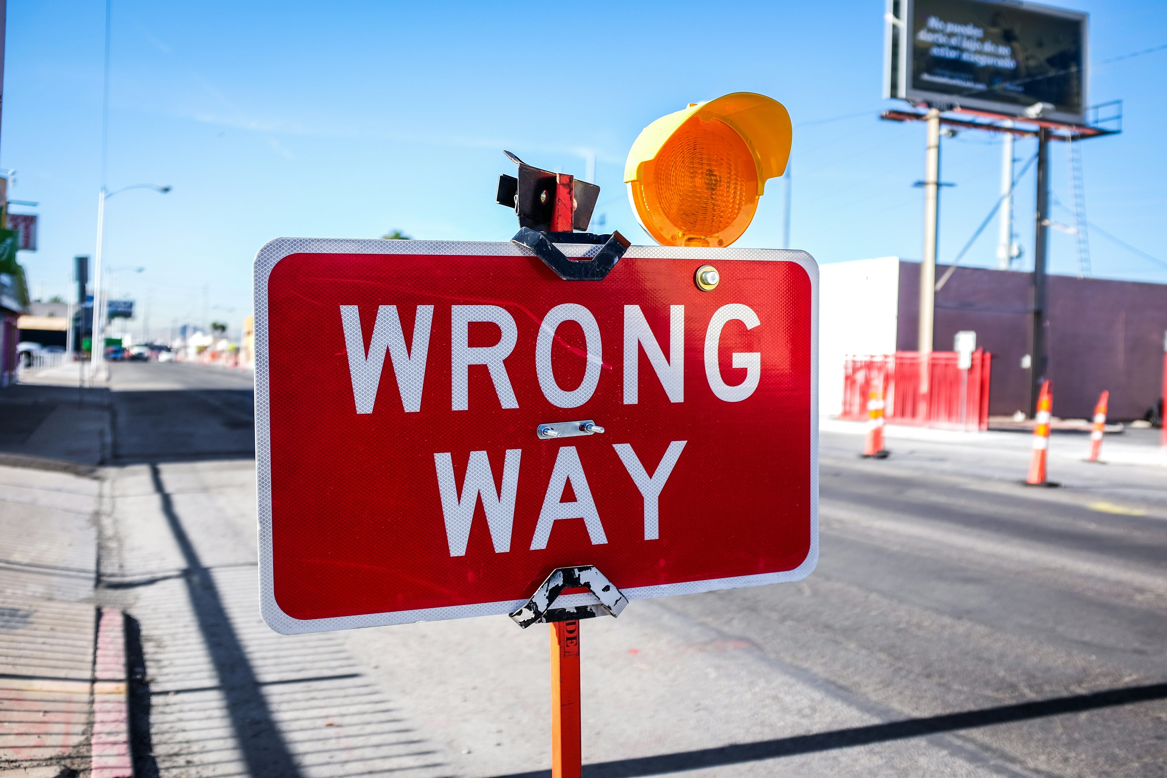 Red 'Wrong Way' sign with warning light, illustrating how promoting senior engineers directly into management roles often takes organisations down the wrong path