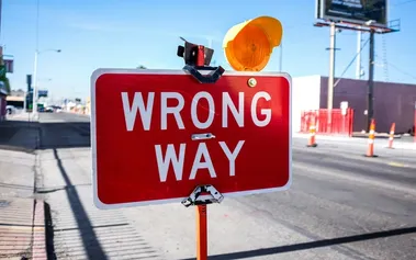 Red 'Wrong Way' sign with warning light, illustrating how promoting senior engineers directly into management roles often takes organisations down the wrong path