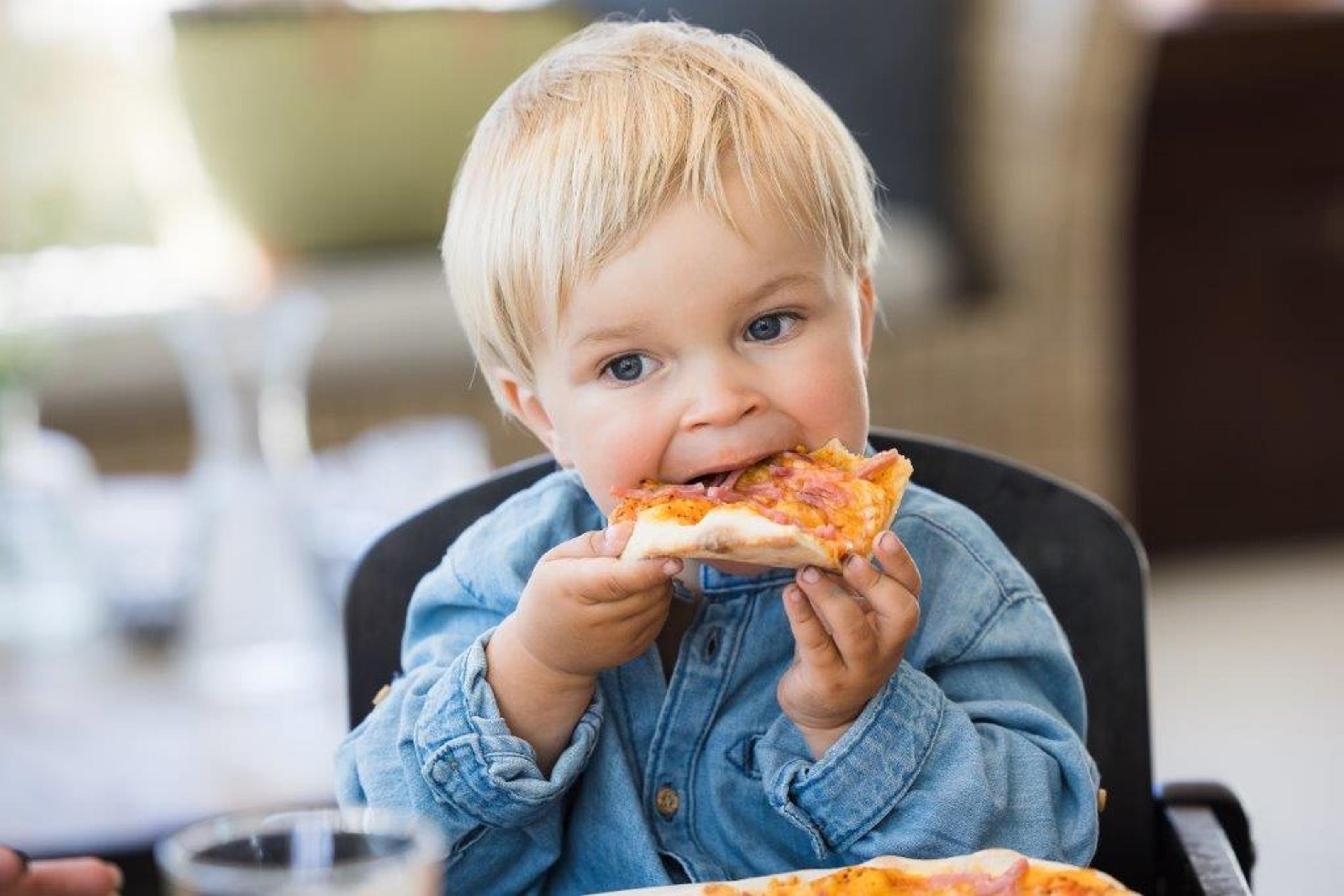 Ett barn äter pizza i restaurang packhuset