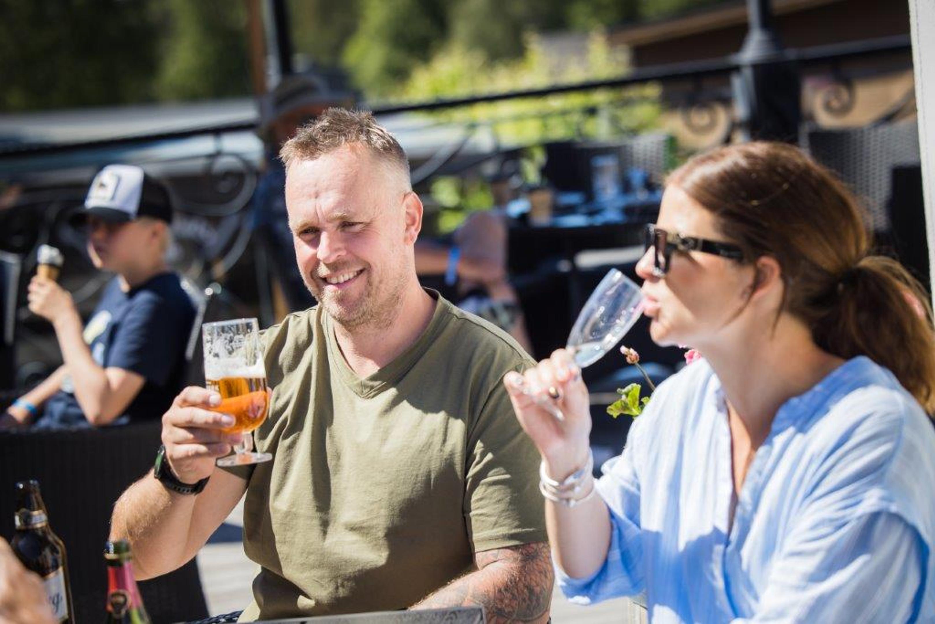 Et par som drikker øl og cava på en av restaurantenes uteserveringer inne på fornøyelsesparken Daftöland.