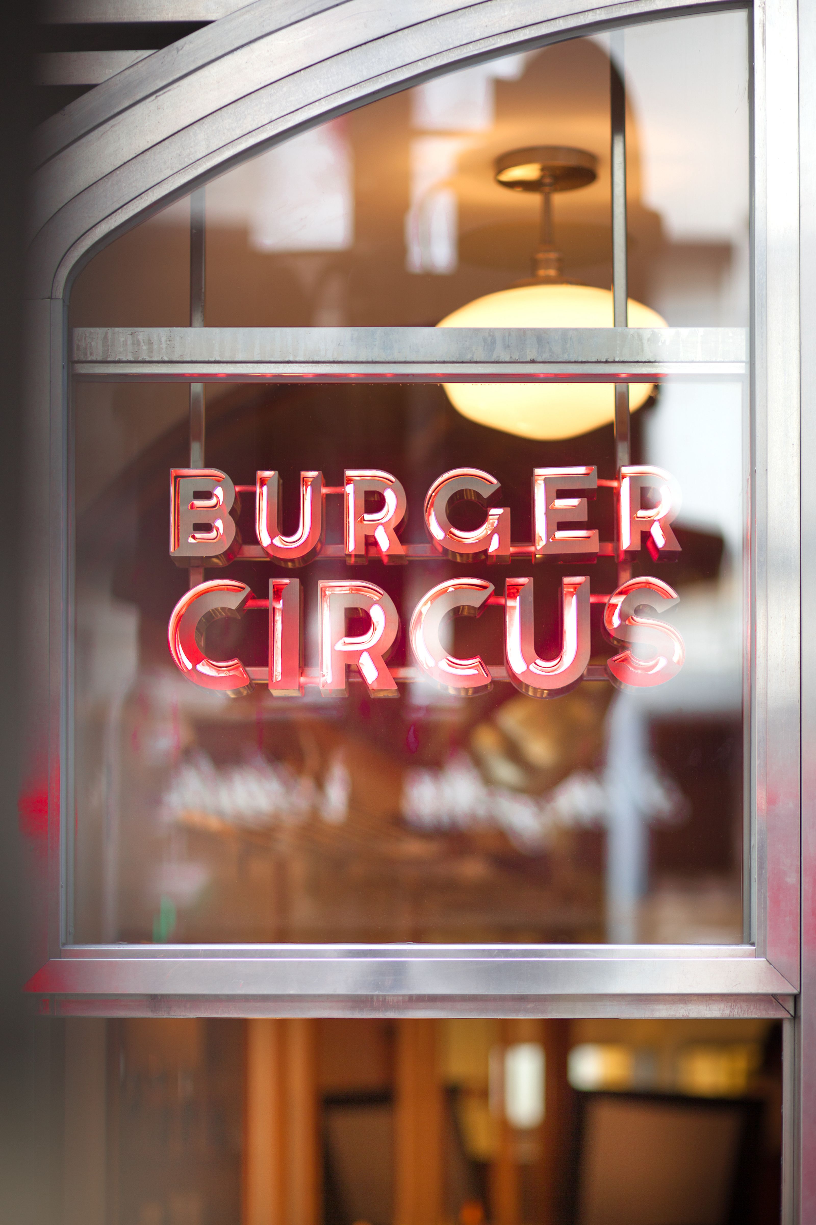 Red neon sign spelling "BURGER CIRCUS" in an Art Deco window.