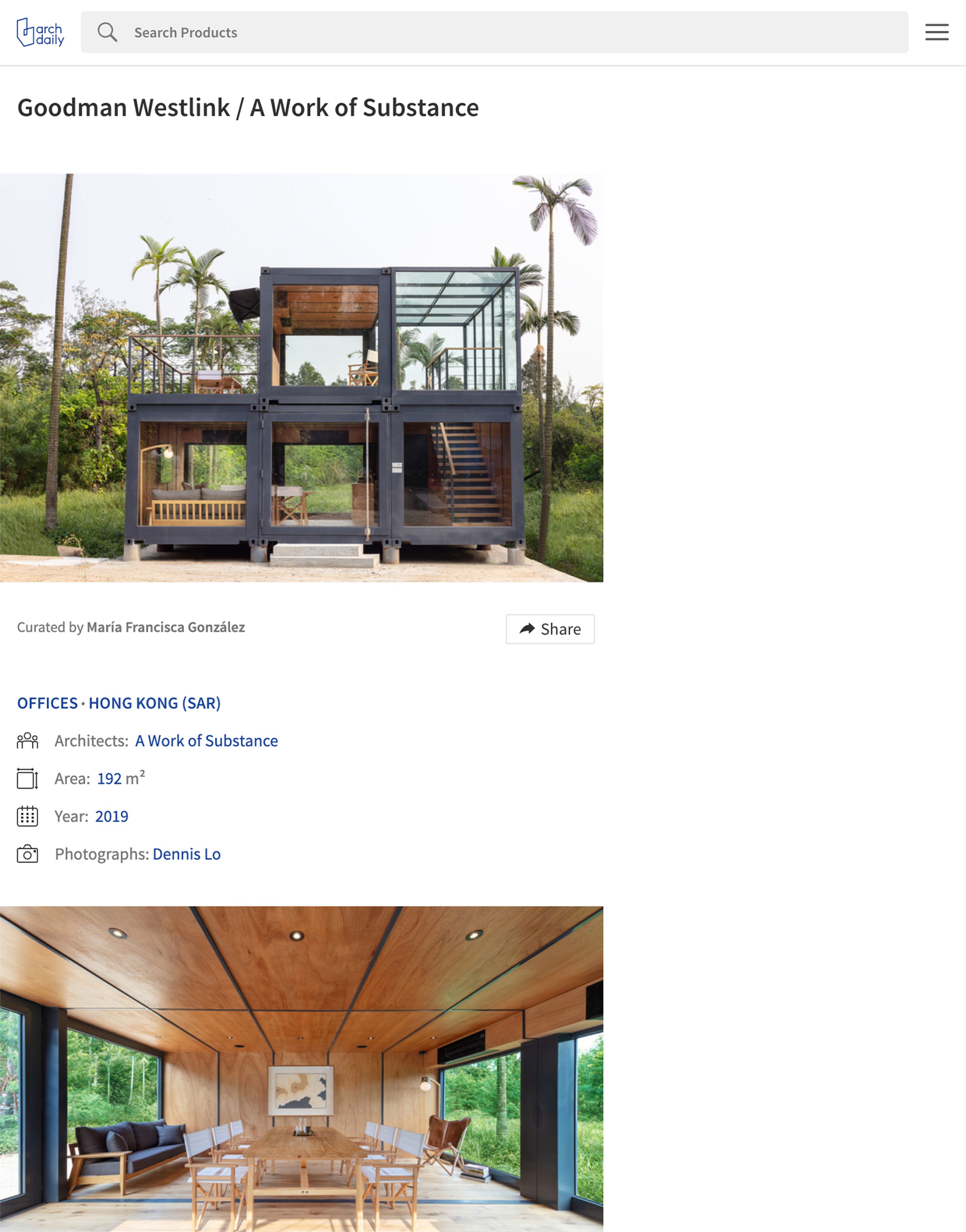 A multi-story building made from dark shipping containers with glass windows, set amidst green trees and palm trees.