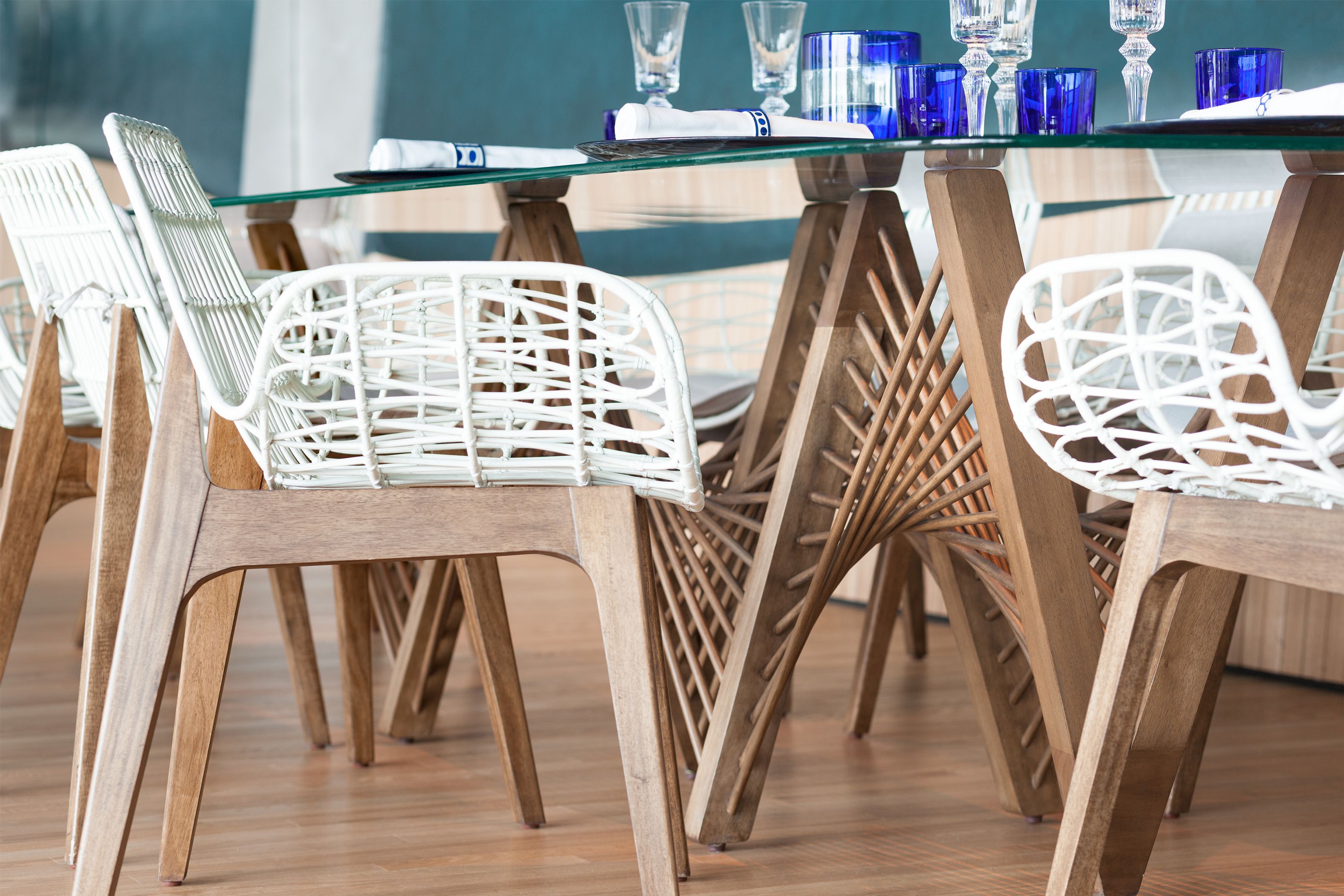 Modern dining table with white slatted chairs and spiraling wooden legs.