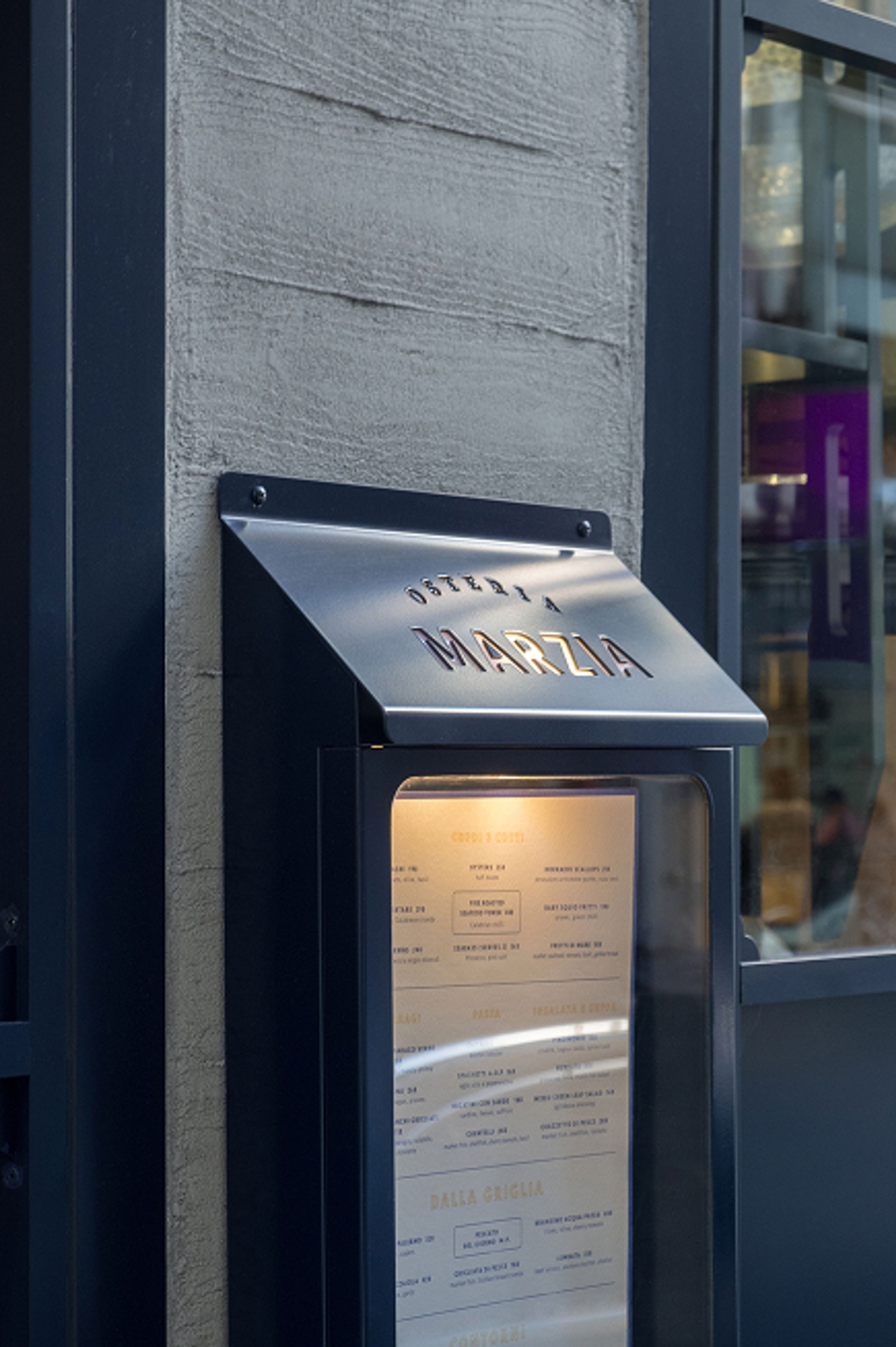 Outdoor menu display for "OSTERIA MARZIA" restaurant.