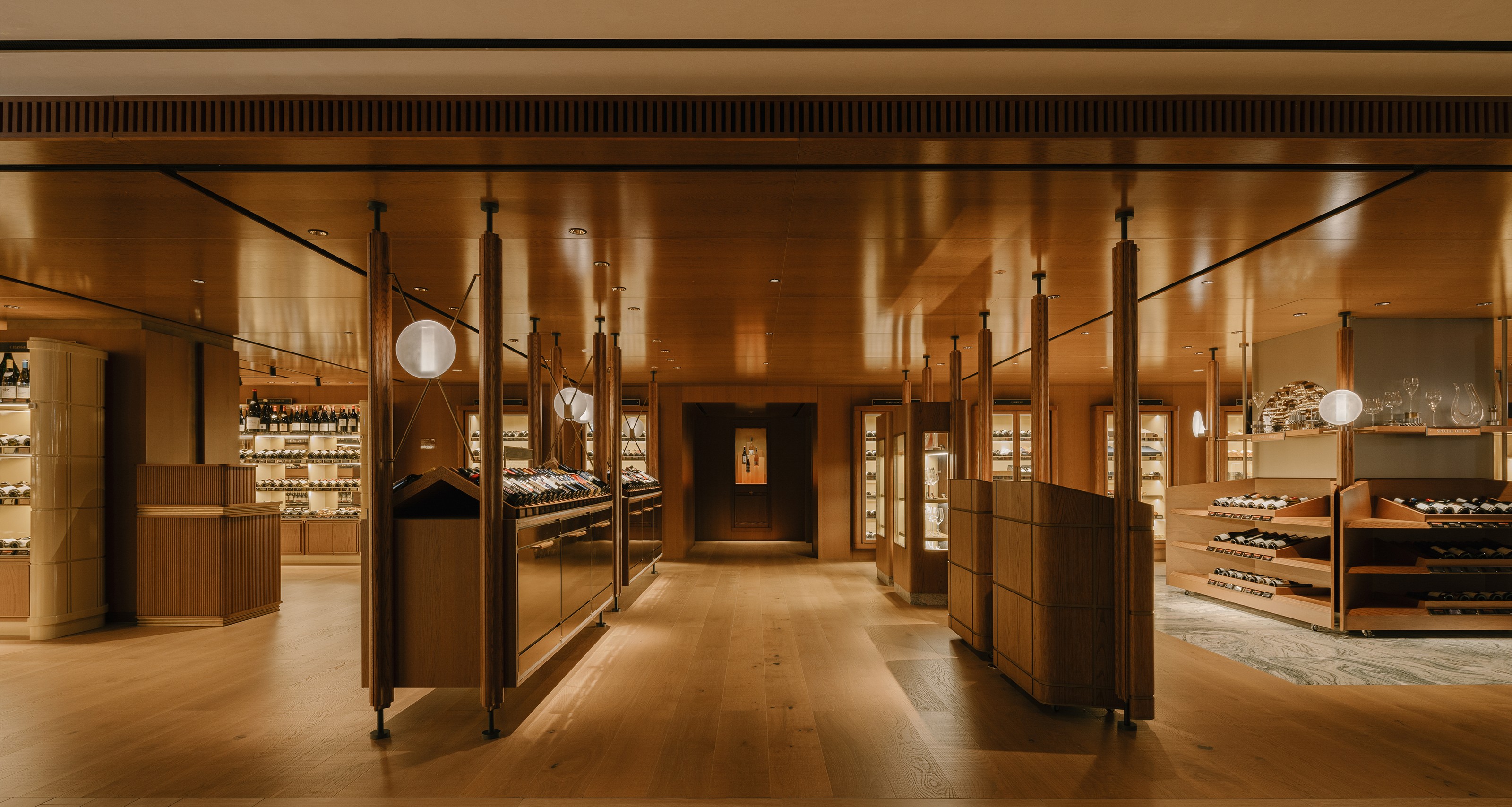 A modern wine store with warm wood architecture and extensive displays of wine bottles.
