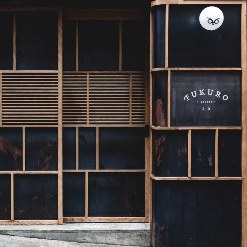 A dark, wood-framed entrance to FUKURO IZAKAYA, featuring an owl logo and the restaurant's name.