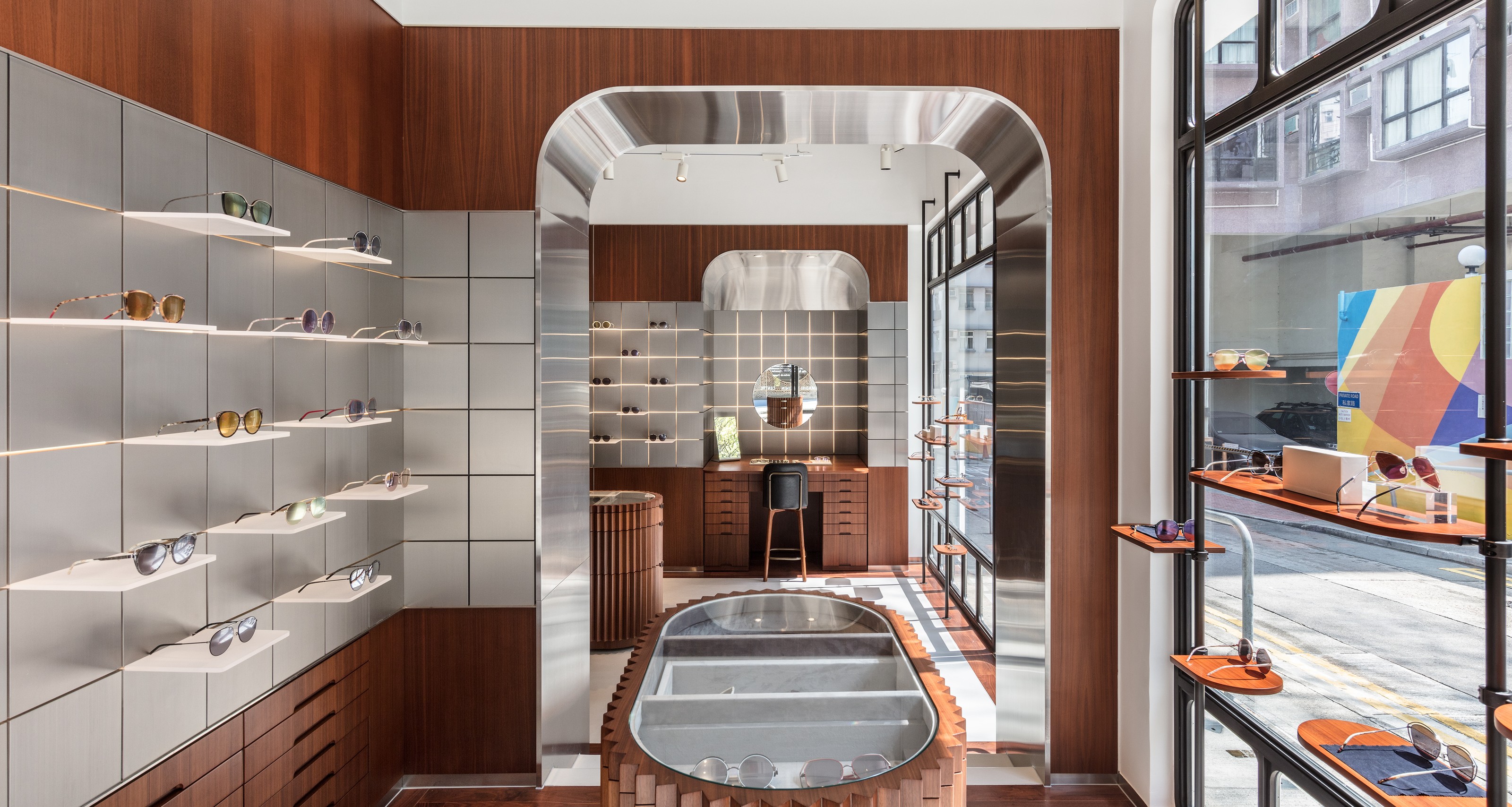 Modern eyewear store interior with glasses displayed on shelves, wood paneling, metallic arches, and a central display case.