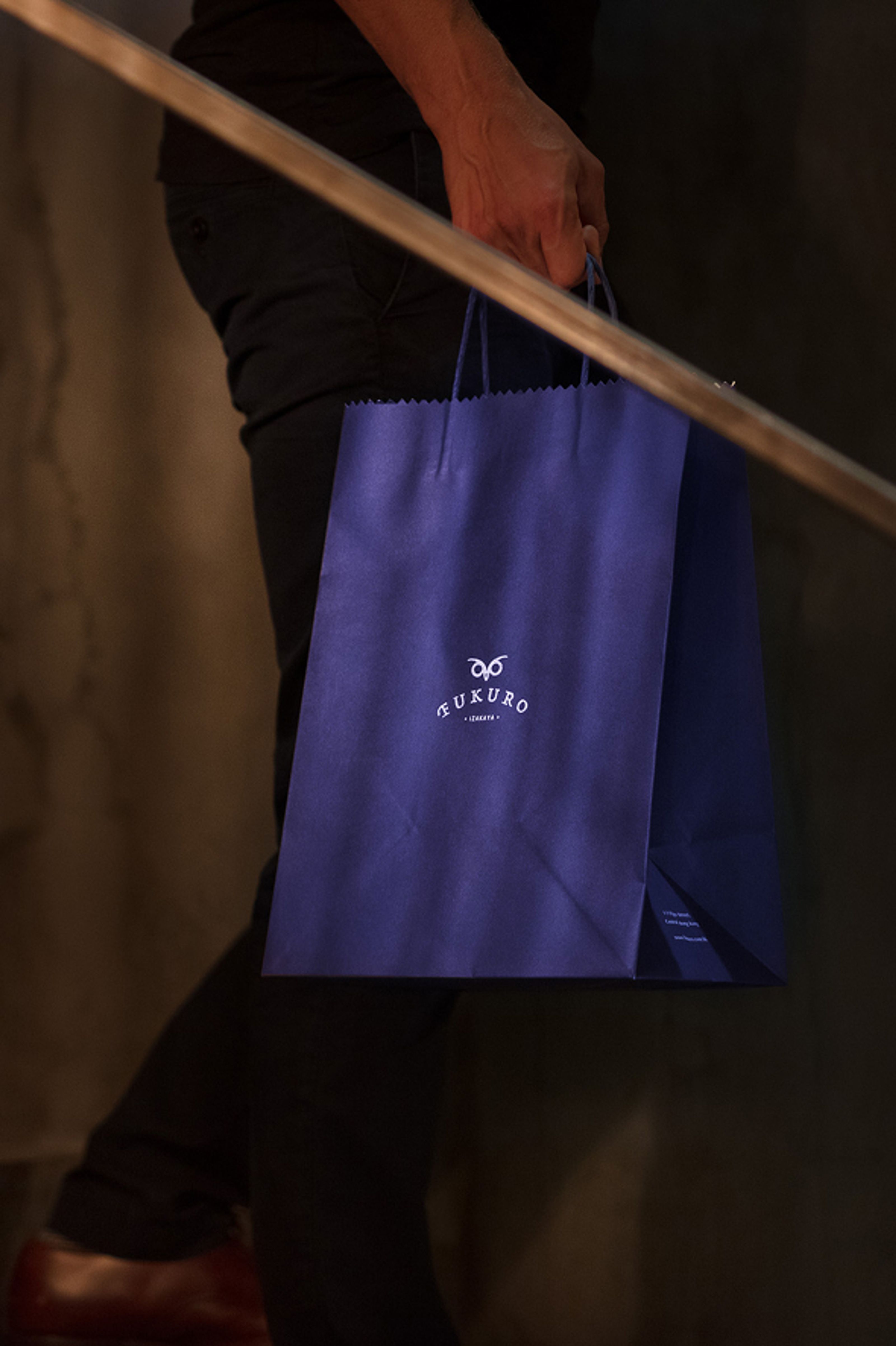 A person carries a dark purple FUKURO shopping bag.