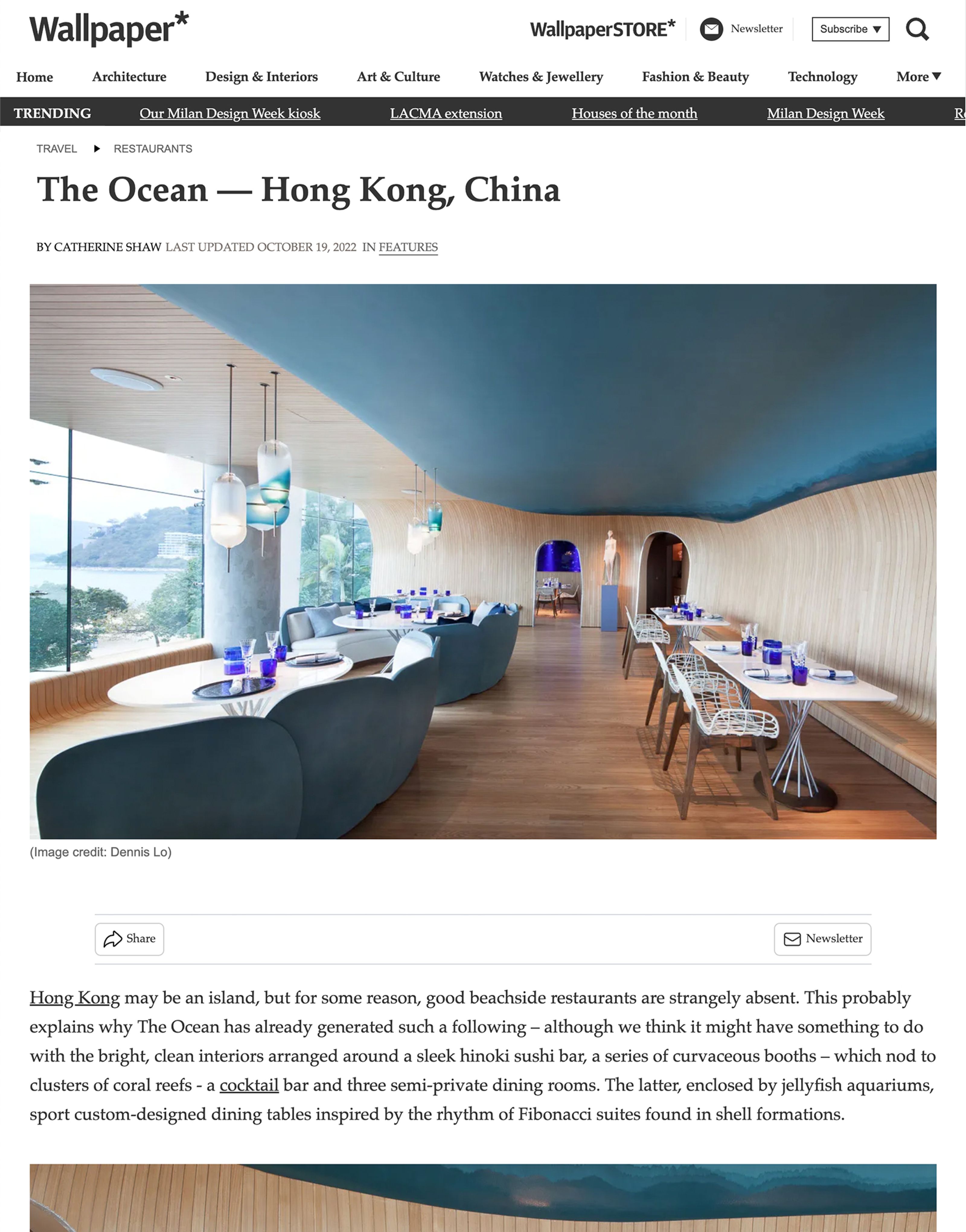 Modern restaurant interior with a blue ceiling, curved wooden walls, and an ocean view.