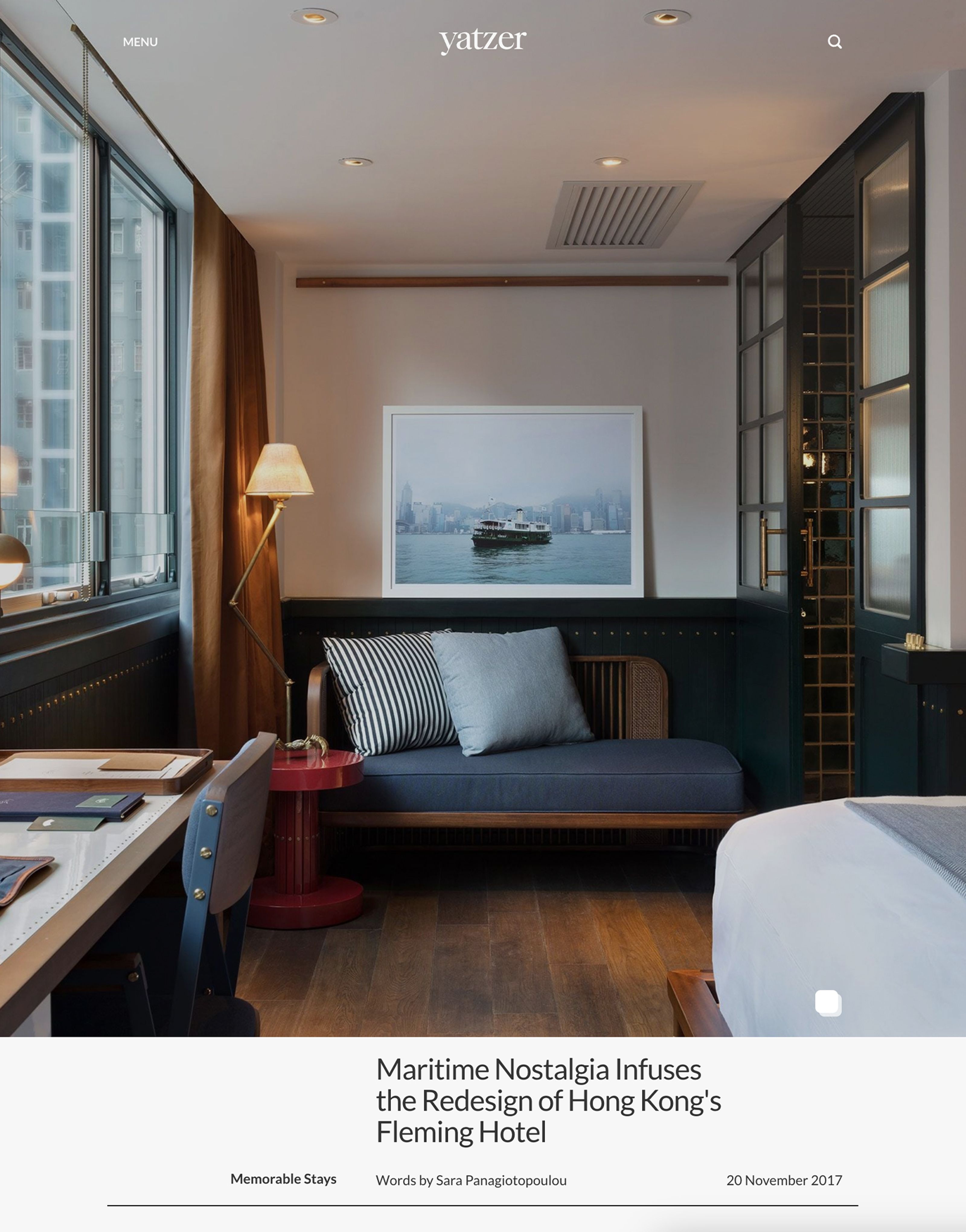 Modern hotel room with a daybed, desk, and a large framed print of a ferry, suggesting a nautical theme.