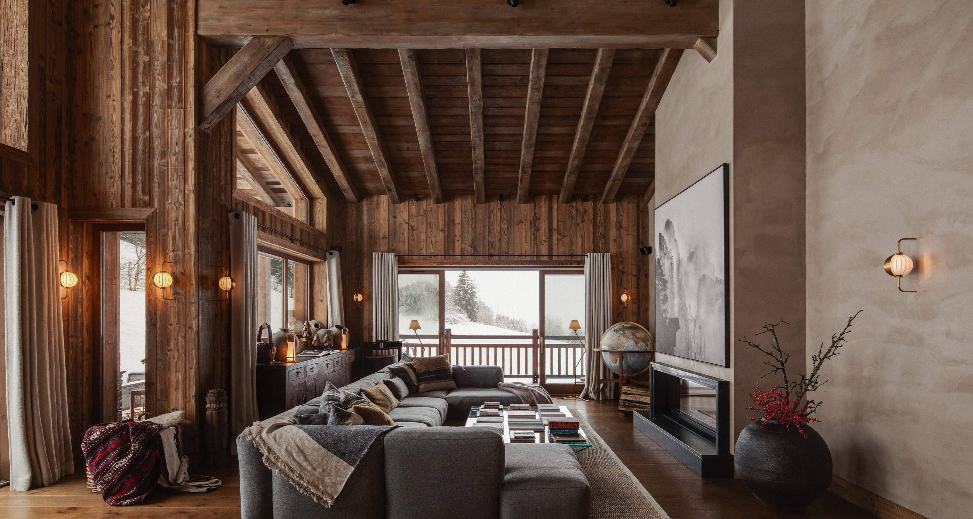 Luxurious ski chalet living room with wooden walls, a large sectional sofa, fireplace, and snowy mountain view.