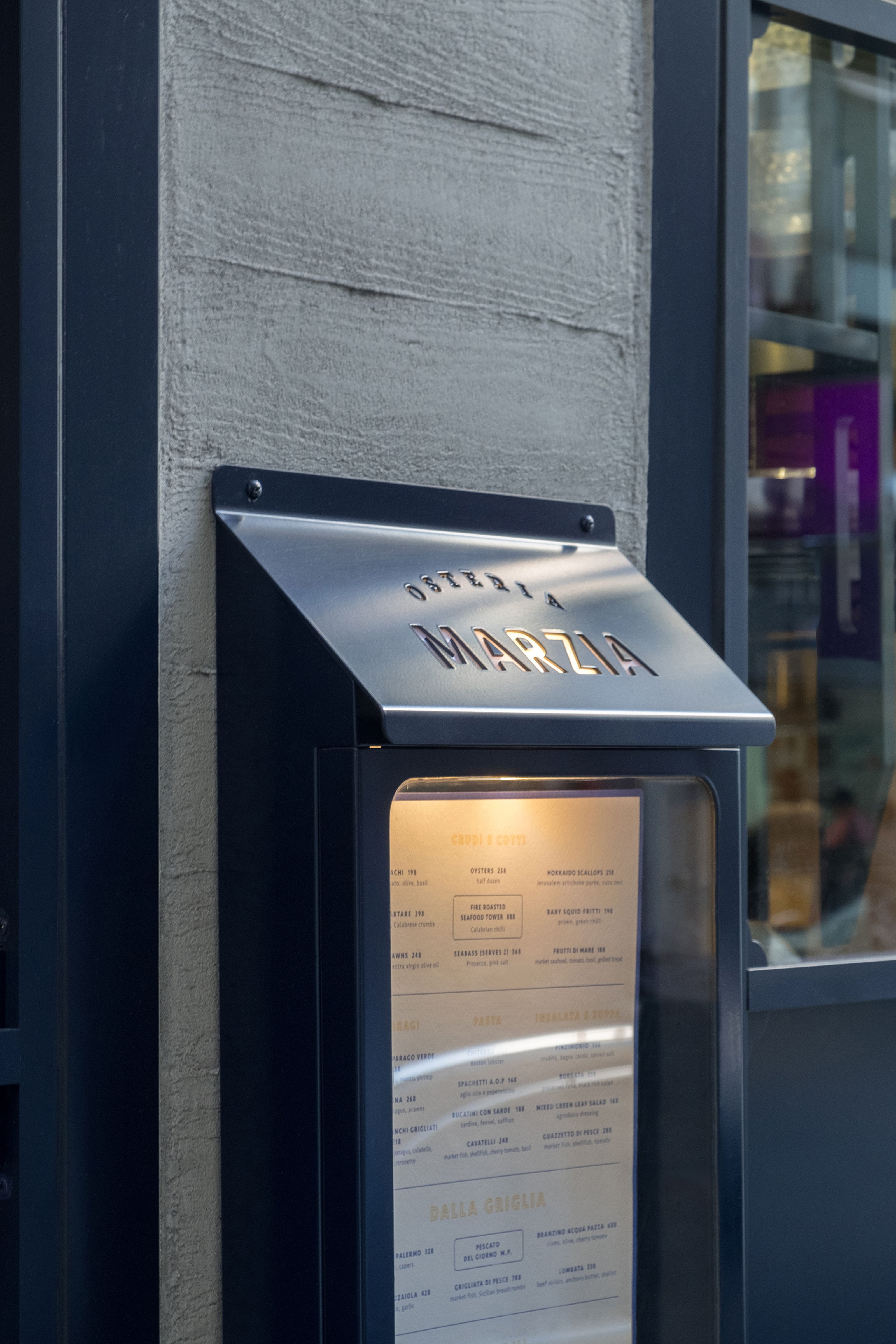 Outdoor menu display for "OSTERIA MARZIA" restaurant.
