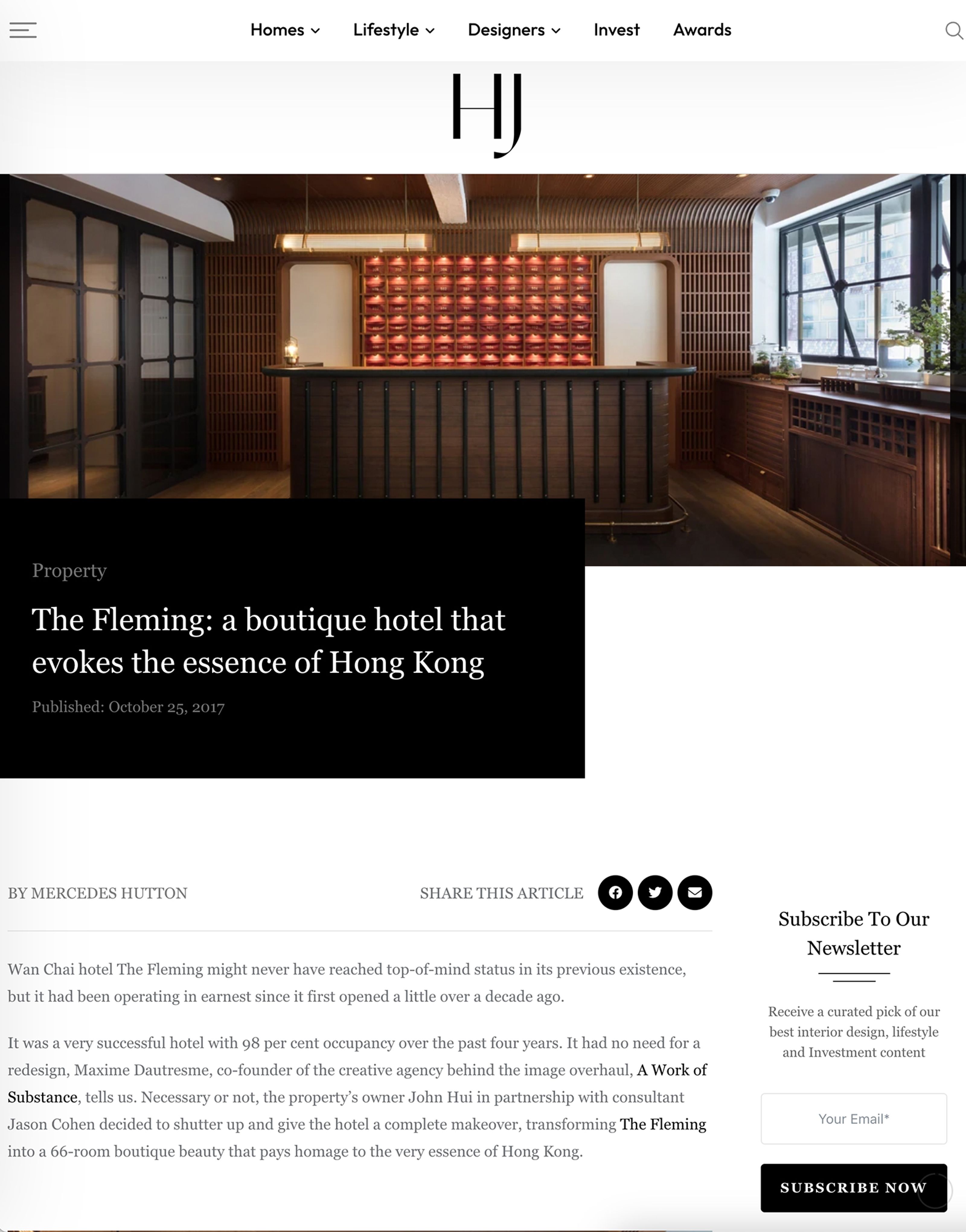 The reception area of The Fleming hotel, featuring a dark wood desk and a backlit terracotta-colored wall.