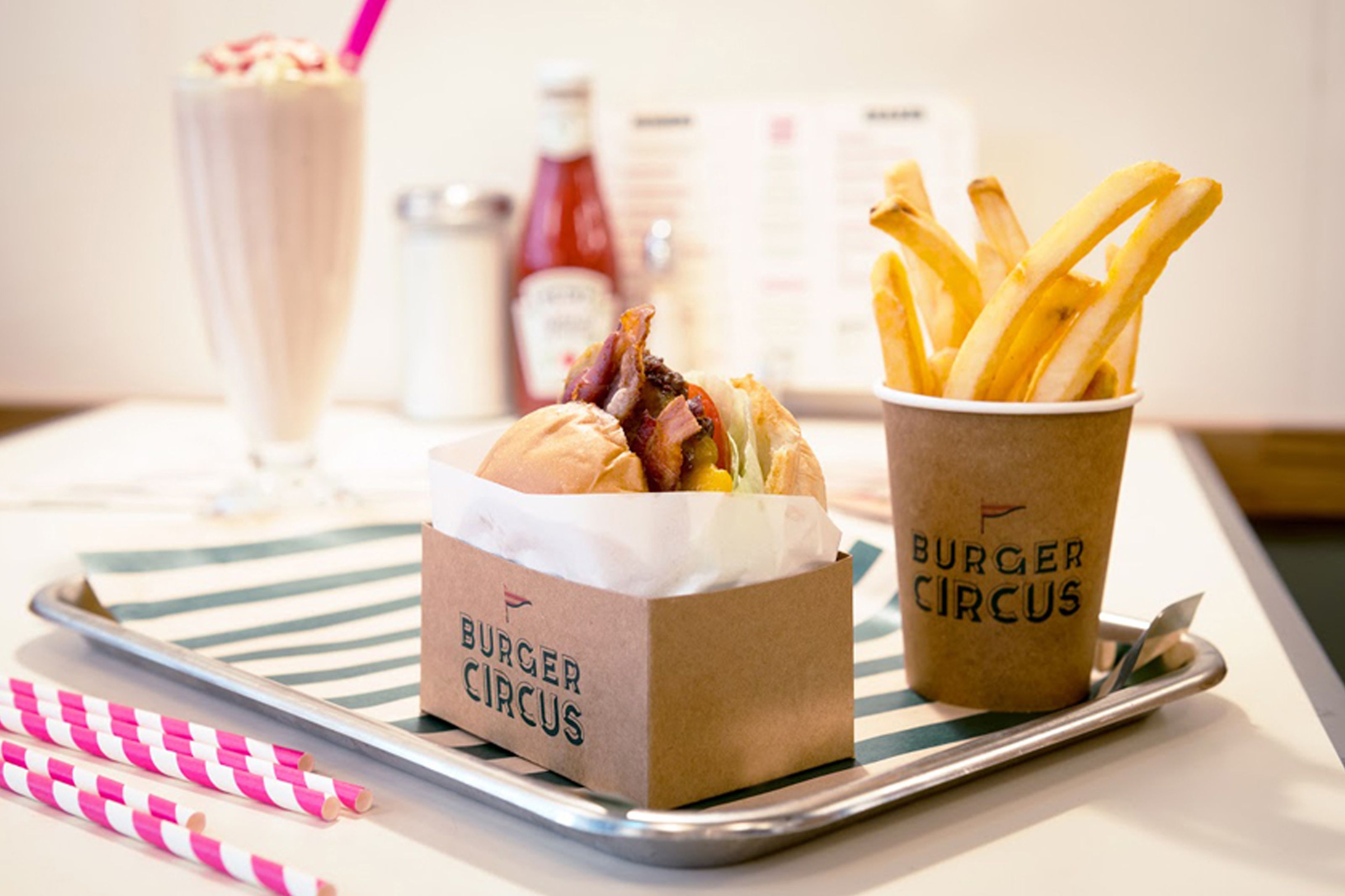 A Burger Circus bacon cheeseburger, fries, and milkshake on a tray.