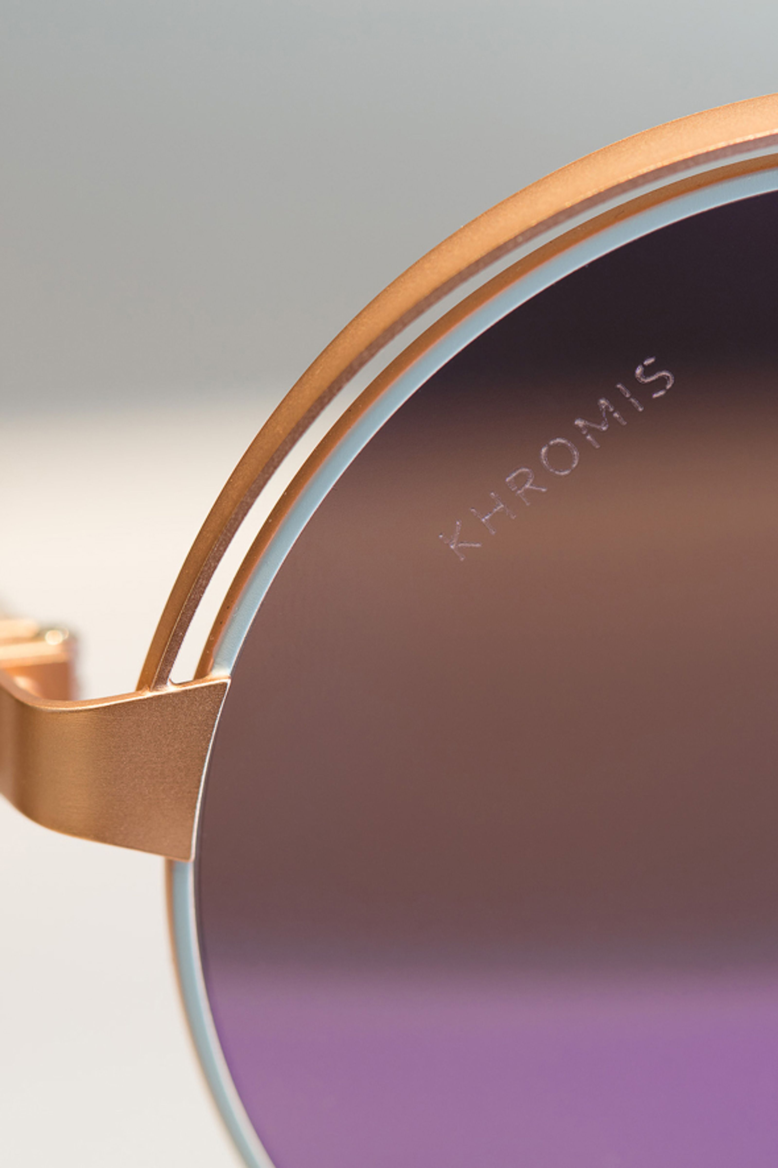 Close-up of a rose gold sunglass with a brown to purple gradient lens, 'KHROMIS' etched on it.