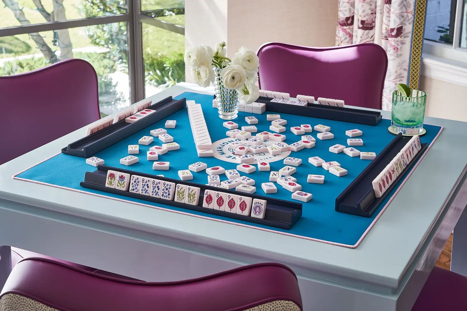 A Mahj Squad mahjong table set with tiles and fresh flowers