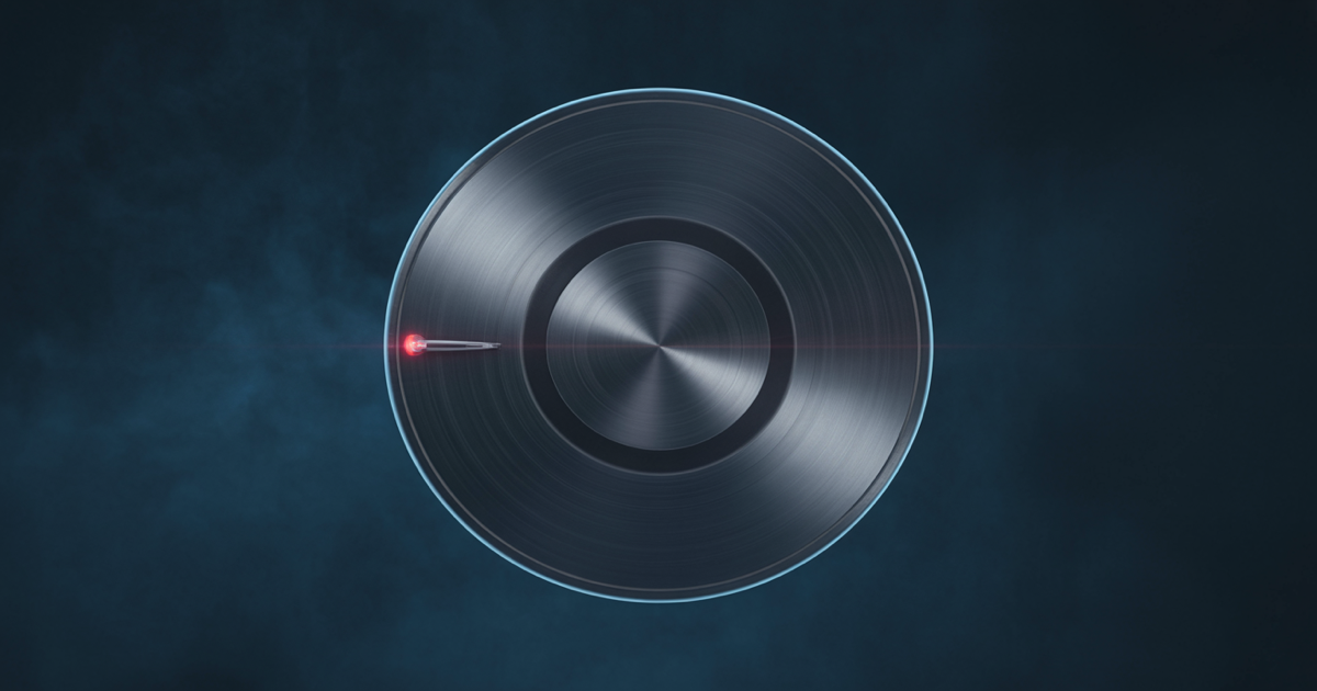 Blank brushed-metal disc with no markings or needle, lit by a soft blue rim light on a dark navy background, a single small red light at its edge