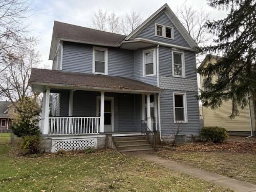 An older gray farmhouse with a wraparound porch, the kind of house families inherit