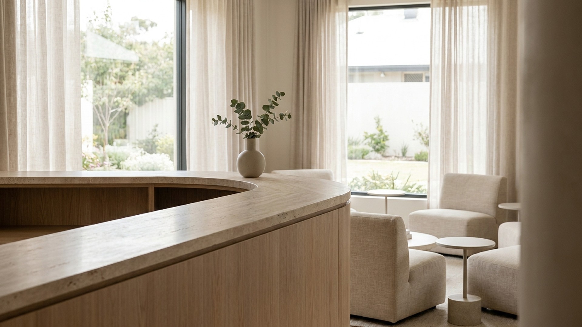 Modern medical spa reception desk in soft daylight, empty waiting chairs, no logos or readable screens.
