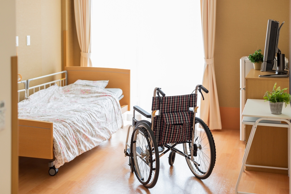Image Empty nursing home room with a wheelchair beside the bed, highlighting Florida nursing home safety concerns and the debate over granny cams.