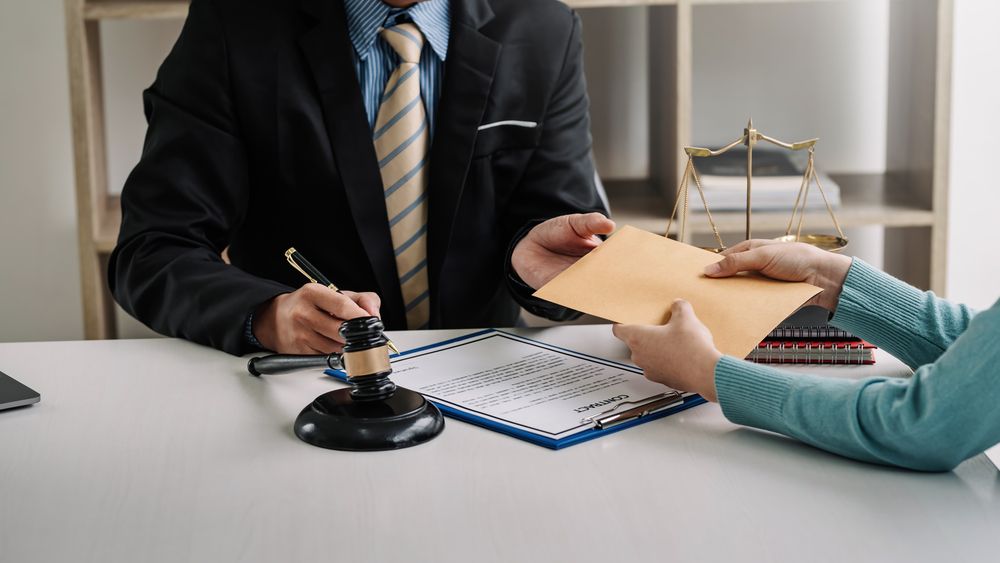 Personal injury attorney reviewing a contract and contingency fee agreement with a client at a desk with a gavel and legal documents.