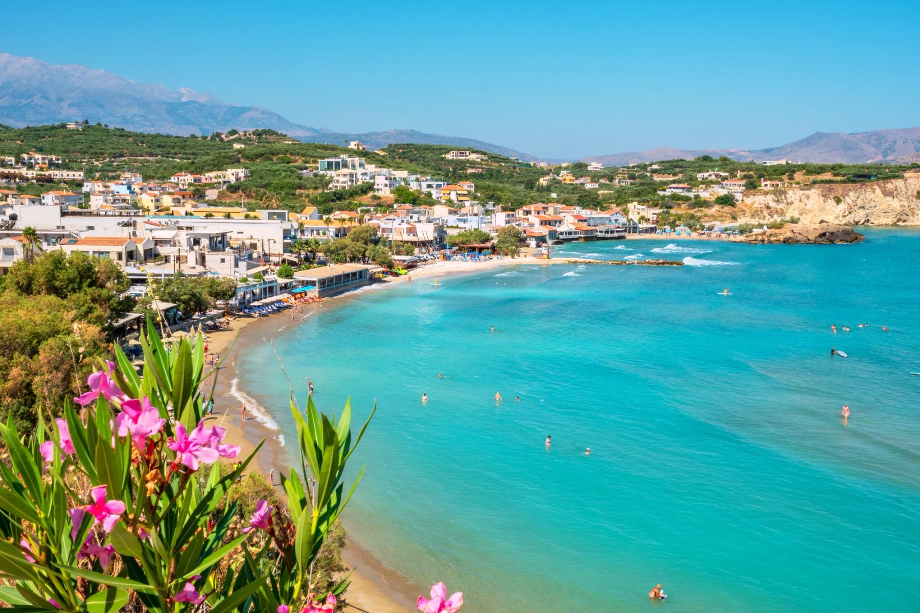 Utsikt över stranden, det azurblå havet och den mysiga byn Almyrida på Kreta, Grekland
